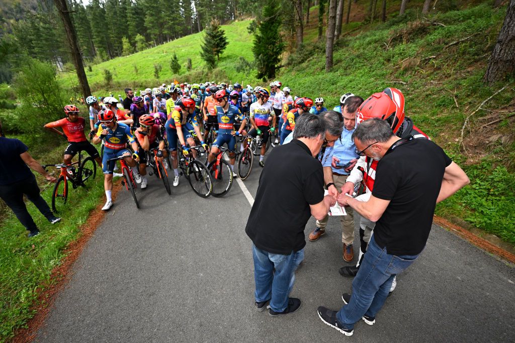 LEGUTIO SPAIN APRIL 04 LR UCI commissaires Francisco Jose Garcia Armendaris Kiko Garcia of Spain and a general view of the peloton waiting at Olaeta 582m after the neutralisation of the race due to a multiple crash during the 63rd Itzulia Basque Country 2024 Stage 4 a 1575km stage from Etxarri Aranatz to Legutio 550m Race neutralised due to a multiple riders crash and dropouts The breakaway will dispute the victory UCIWT on April 04 2024 in Etxarri Legutio Spain Photo by Tim de WaeleGetty Images