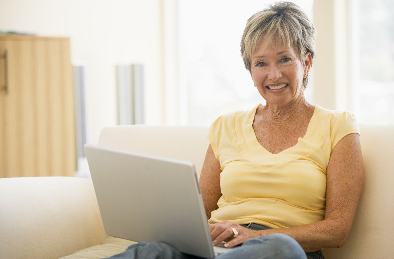 Woman in living room with laptop smiling