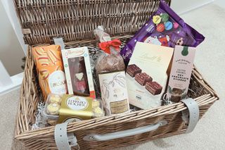A hamper filled with chocolate treats including hot chocolate, hot chocolate stirrer, box of chocolates, Ferrero Rochers and more