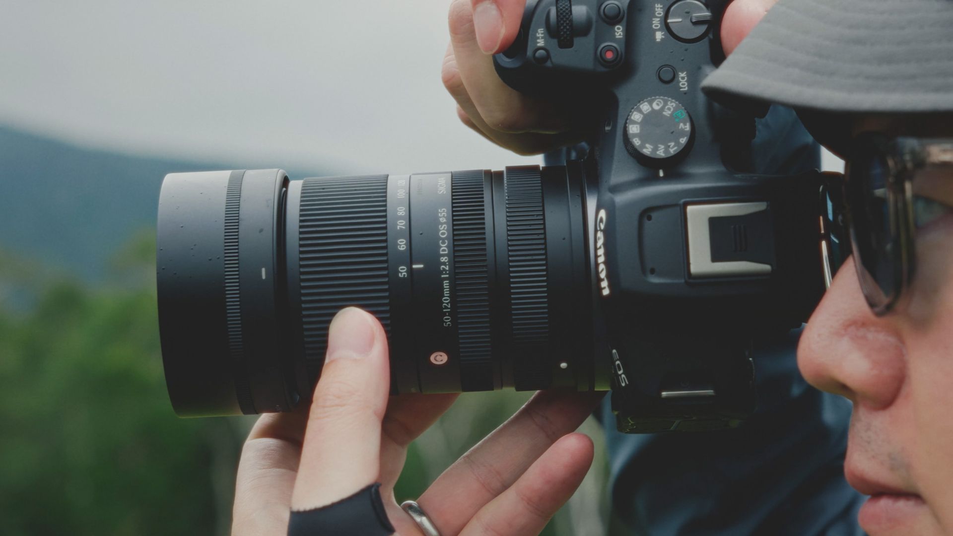Sigma 50-120mm F2.8 DC OS Contemporary lens attached to a Canon camera, held by a photographer outdoors