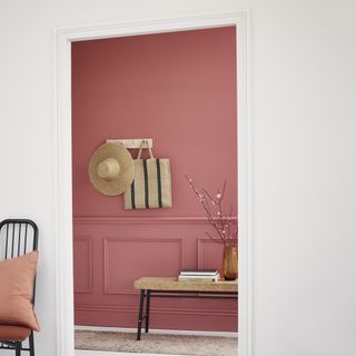pink entryway with painted panelling, bench, shaker peg rail with hat/basket