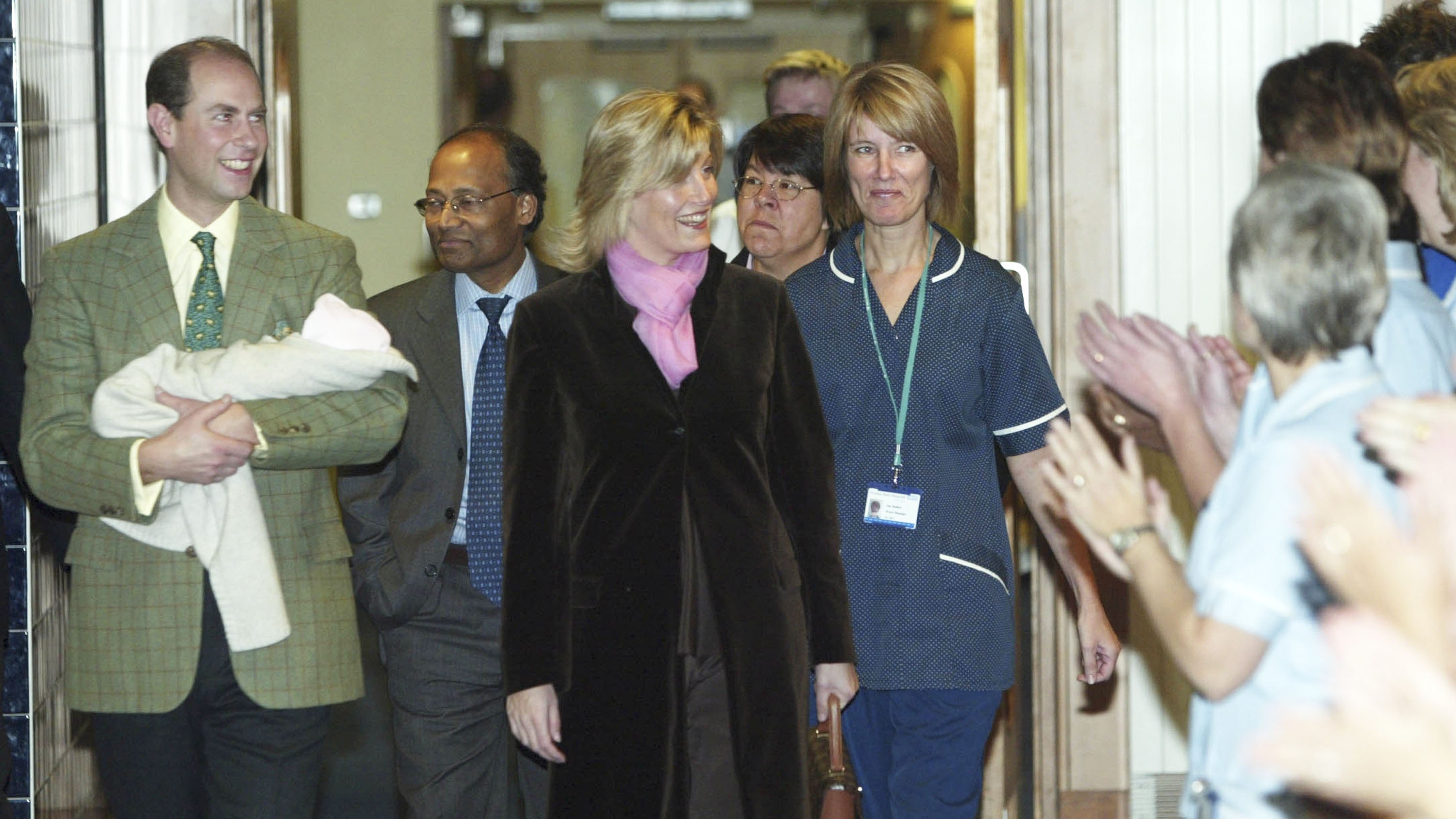 Prince Edward (carrying baby Louise) and Sophie smile as people clap outside Frimley Park Hospital on November 23, 2003