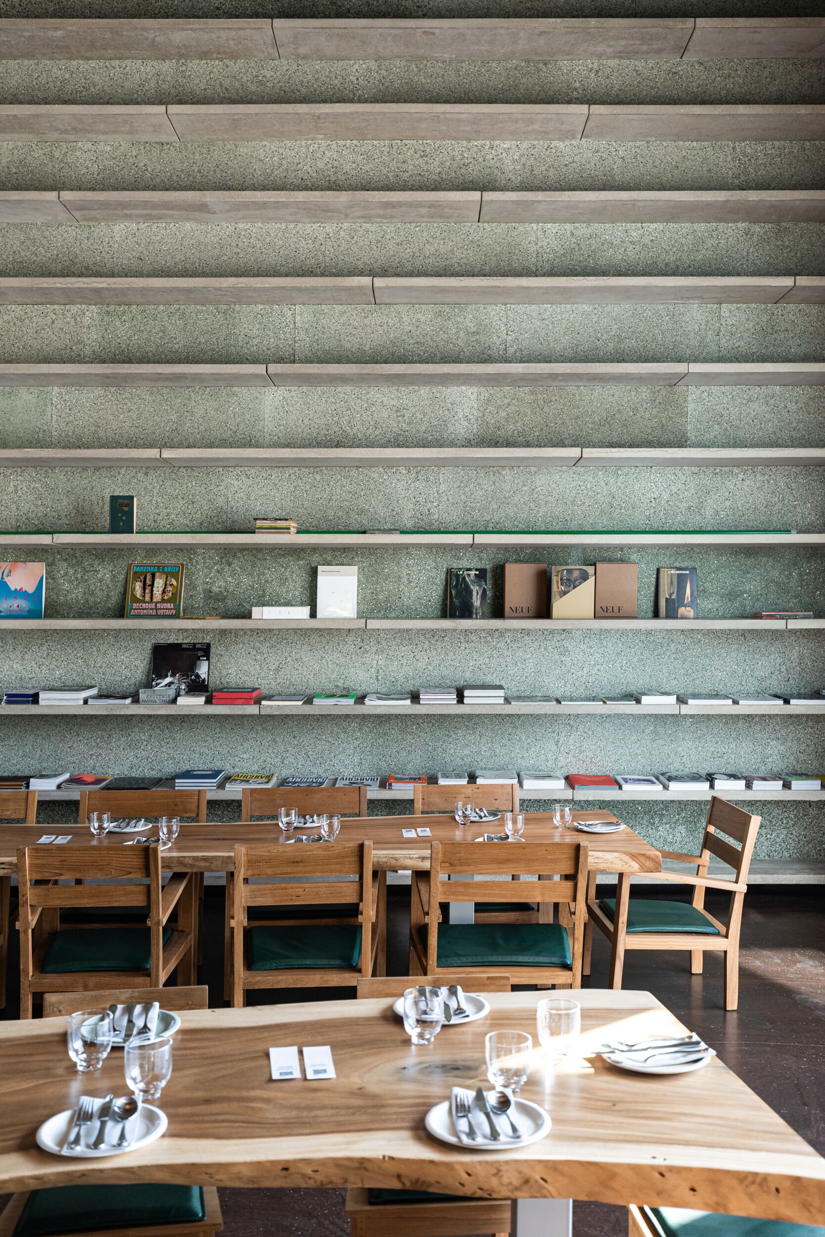 A brutalist cafe with wooden, uneven tables and chairs.