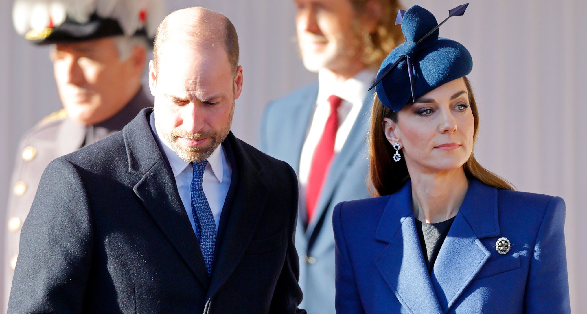 Prince William wearing a dark coat putting his arm around Kate, in a blue coat and hat