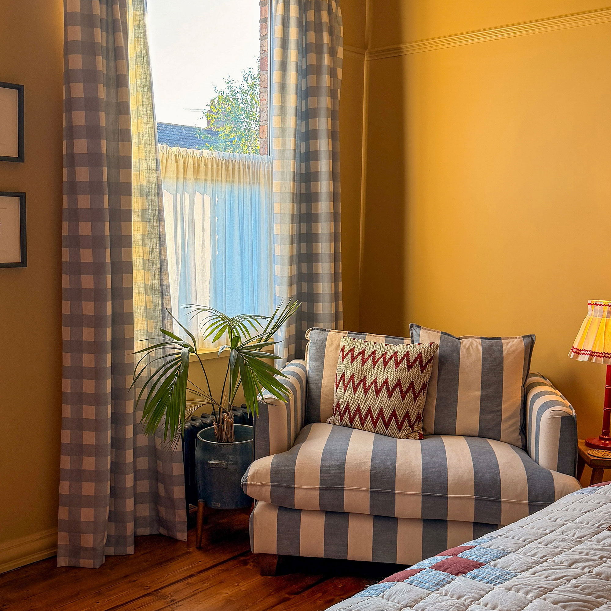 Blue and white striped loveseat in yellow bedroom with blue and white gingham curtains
