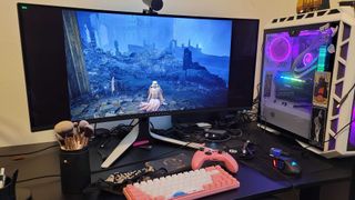 Alienware Monitor playing elden ring on a very cluttered desk uwu