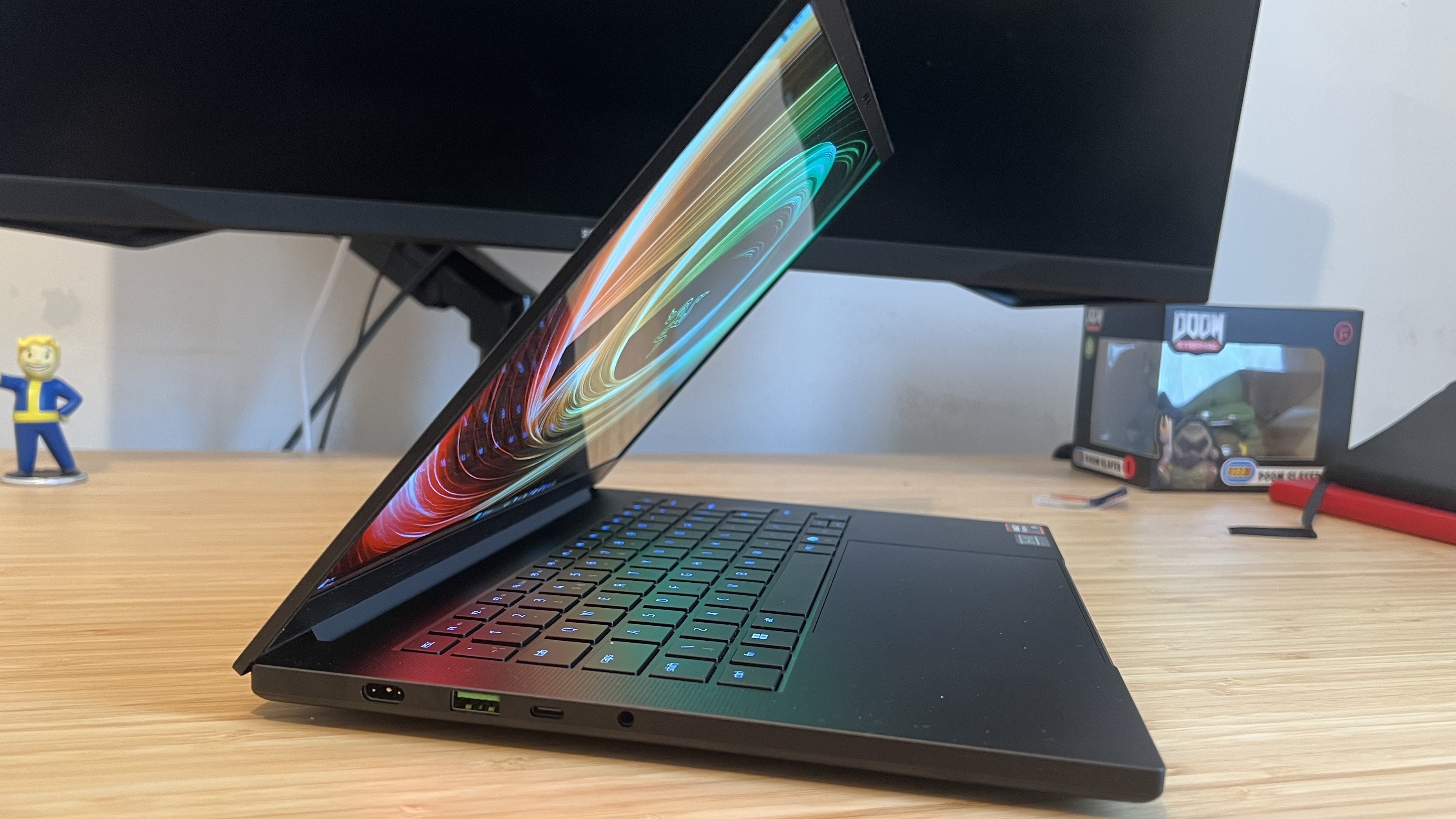 Side view of Razer Blade 14 laptop with lid open on a wooden desk