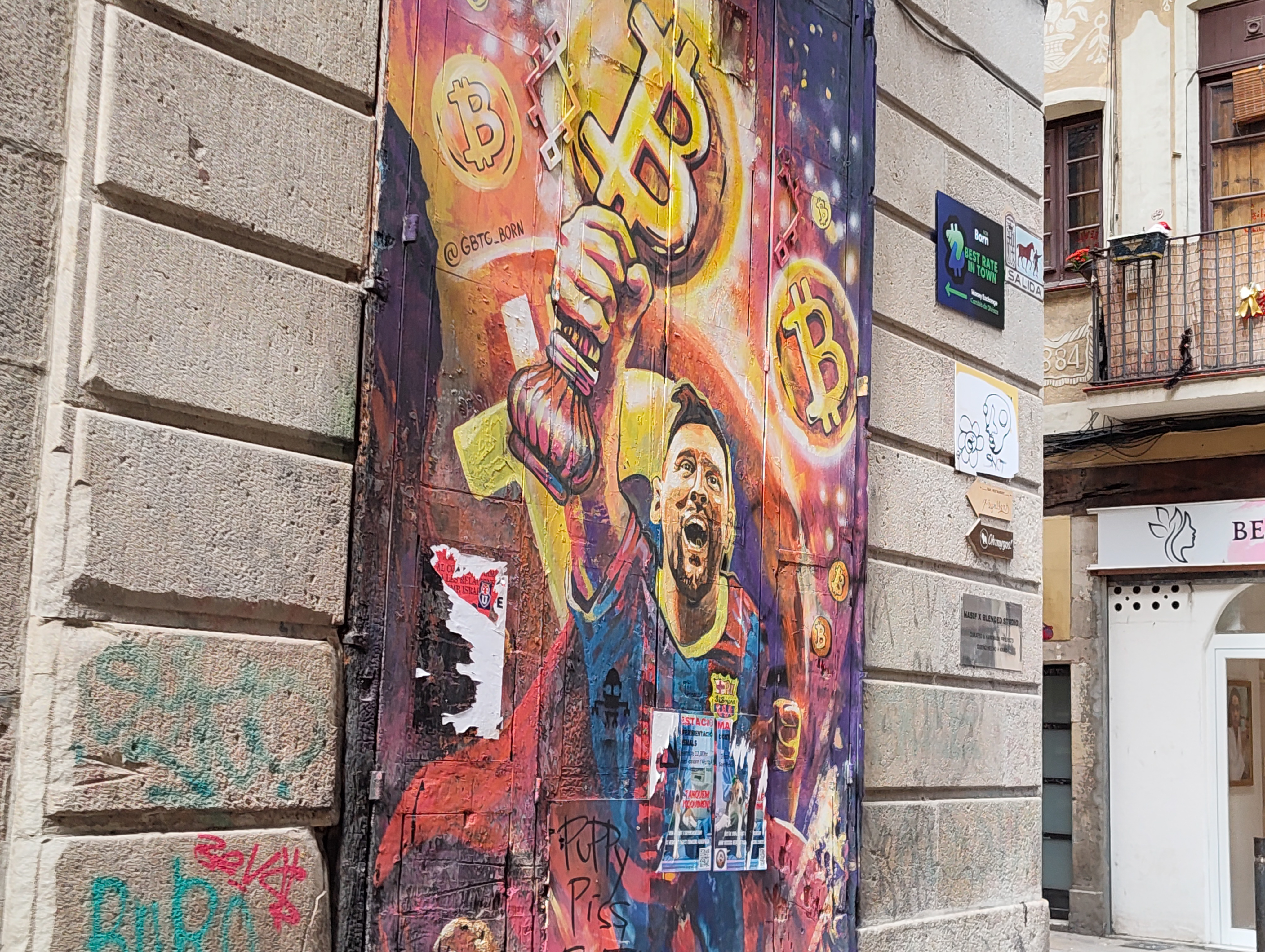 Street mural featuring a footballer holding a glowing Bitcoin symbol painted on a door in Barcelona, photographed with the Nothing Phone (4a).