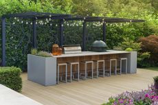 outdoor kitchen on deck with pergola overhanging with fairy lights, bar seats, a BBQ, komodo bbq, and two hurricane lanterns