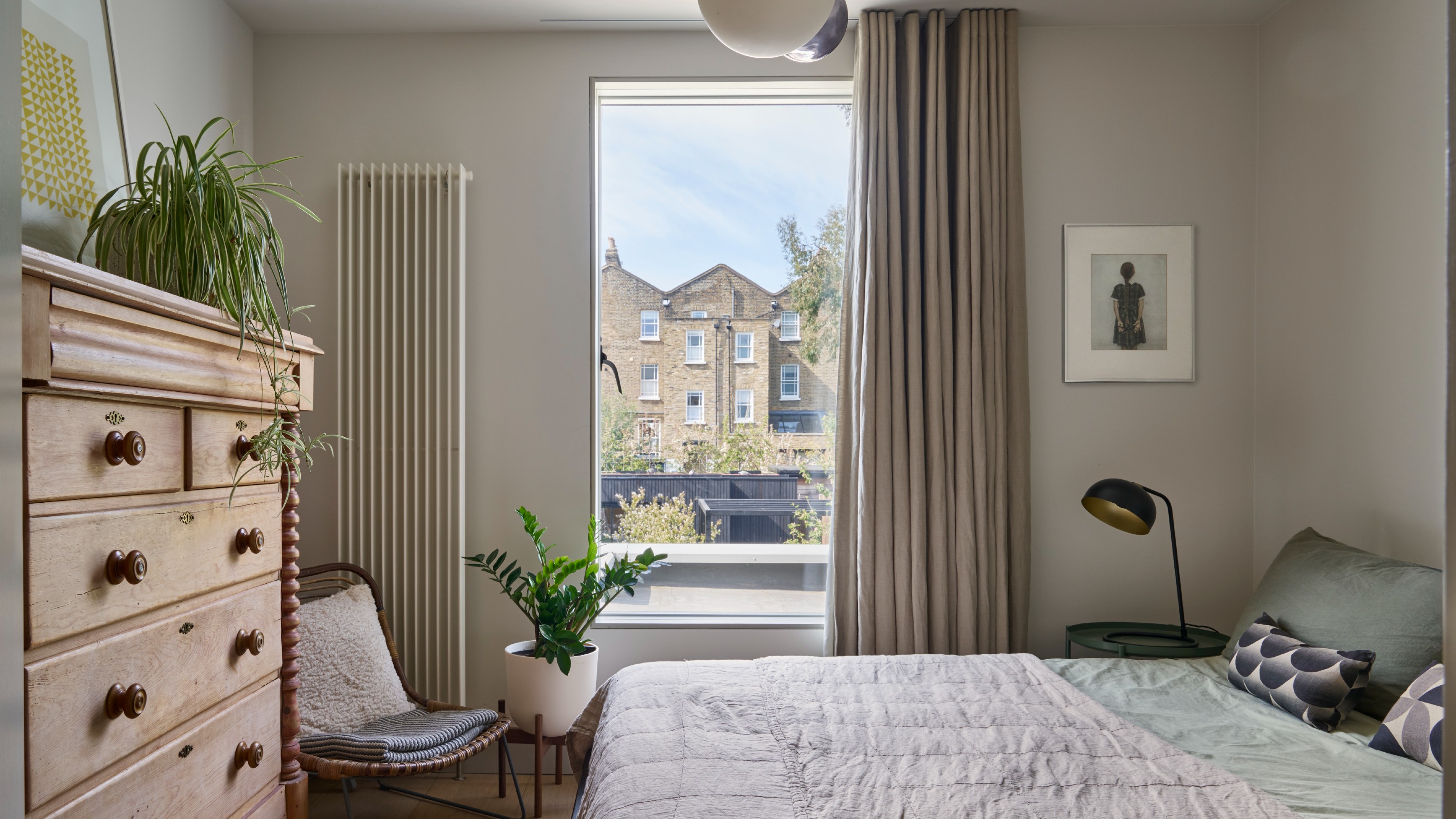 A neutral bedroom painted in a greige colour with beige curtains