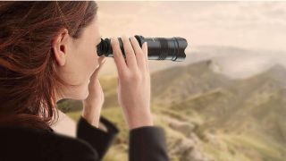 A woman uses one of the best monocular devices to look over a vast landscape