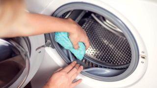 Someone cleaning a washer gasket with a cloth