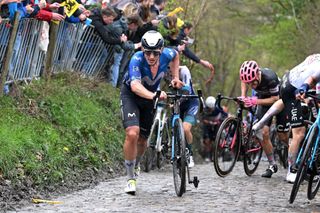 Ivan Garcia Cortina (Movistar Team) walks up the slippery slopes of the Koppenberg cobblestones sector at the 2024 Tour of Flanders