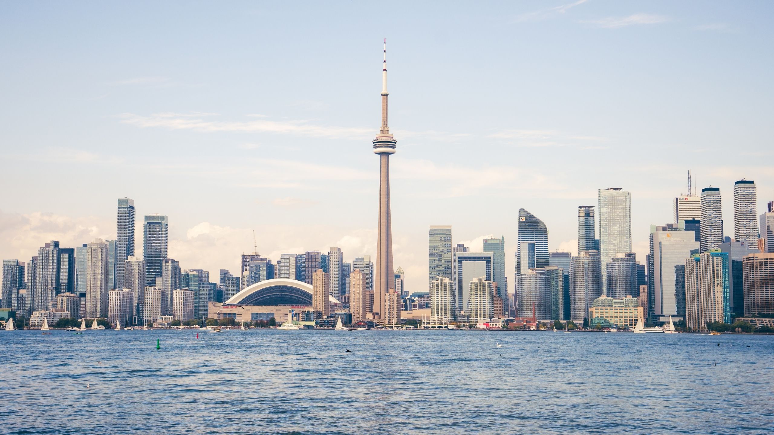 A metropolis' skyline captured at dusk from the water as skyscrapers stand out against its waves and a clear yet pale sky.