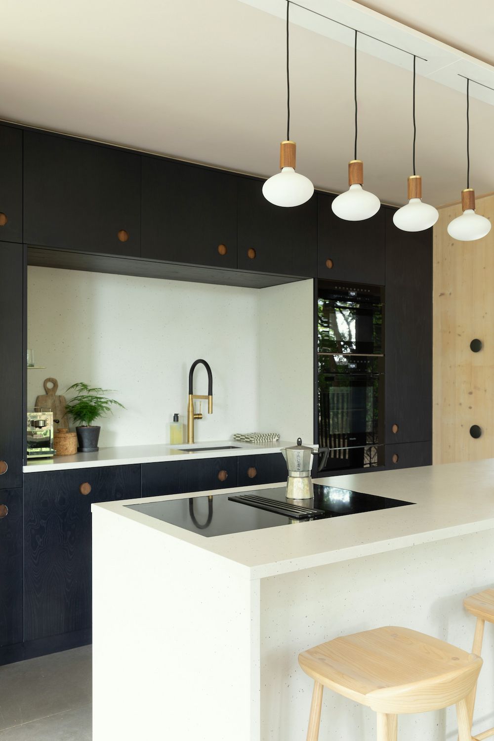 A kitchen with a white splash back and a pendant light hanging over a kitchen island