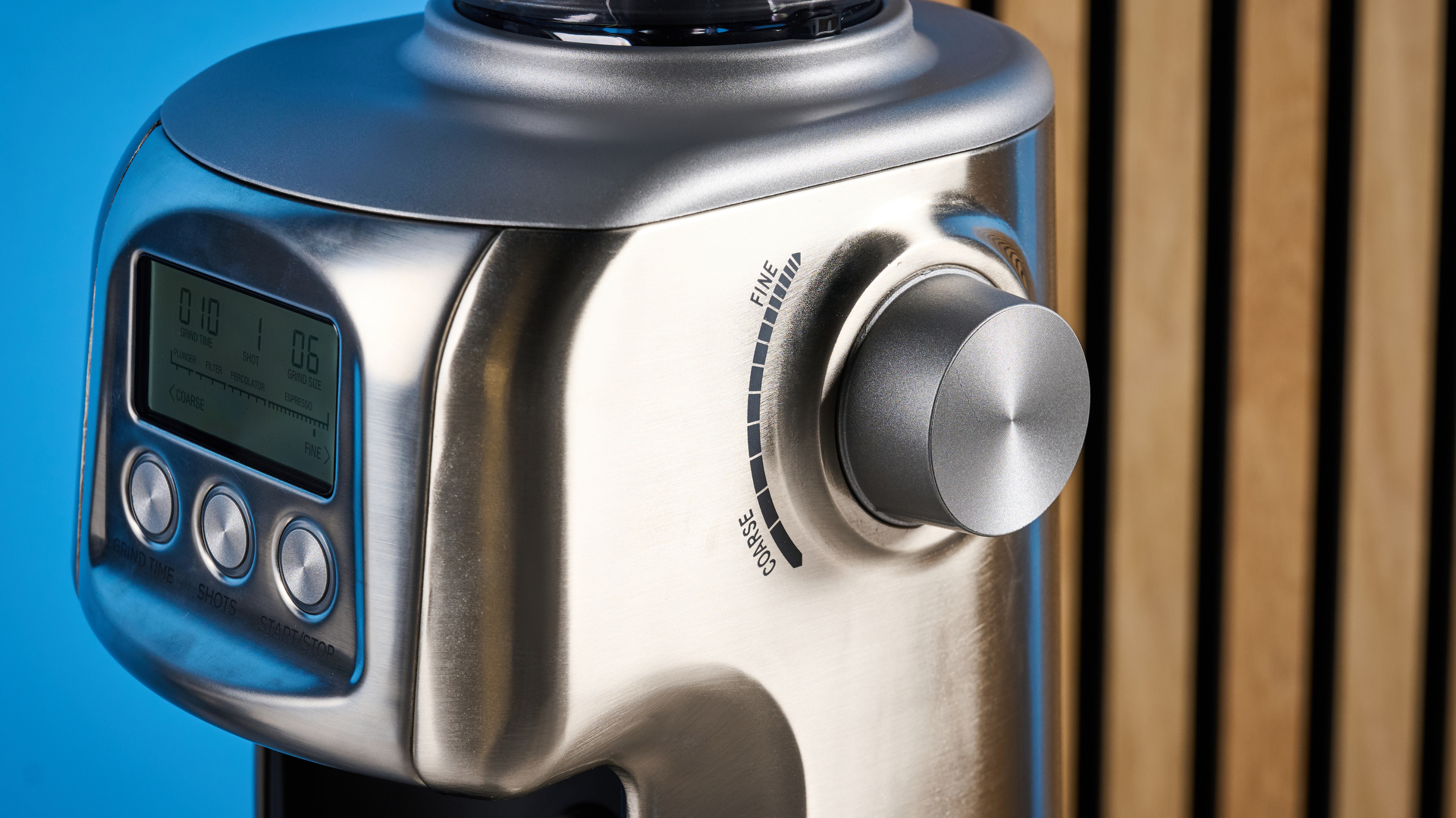 the casabrews tornado coffee grinder in silver showing the LED screen, grind adjustment dial, and photographed against a blue background