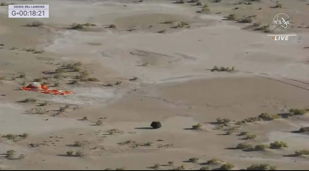 The sample capsule is seen next to the parachute on the ground.