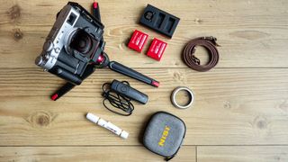 Fujifilm X100V and camera accessories on a wooden floor