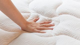 A hand pressing down on the Viscosoft Copper Mattress Pad