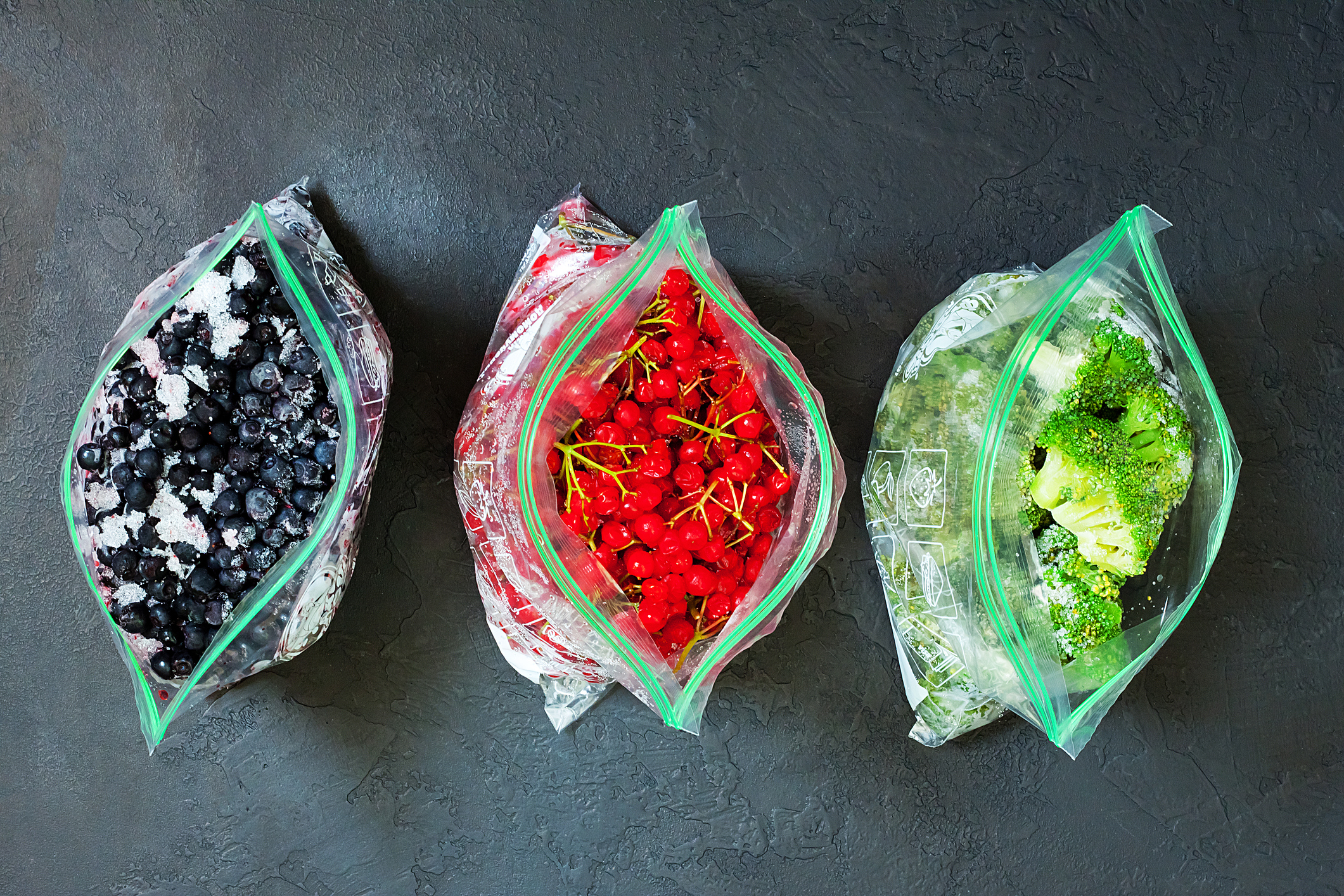Three bags of frozen blueberries, red currants and broccoli, fresh from the freezer