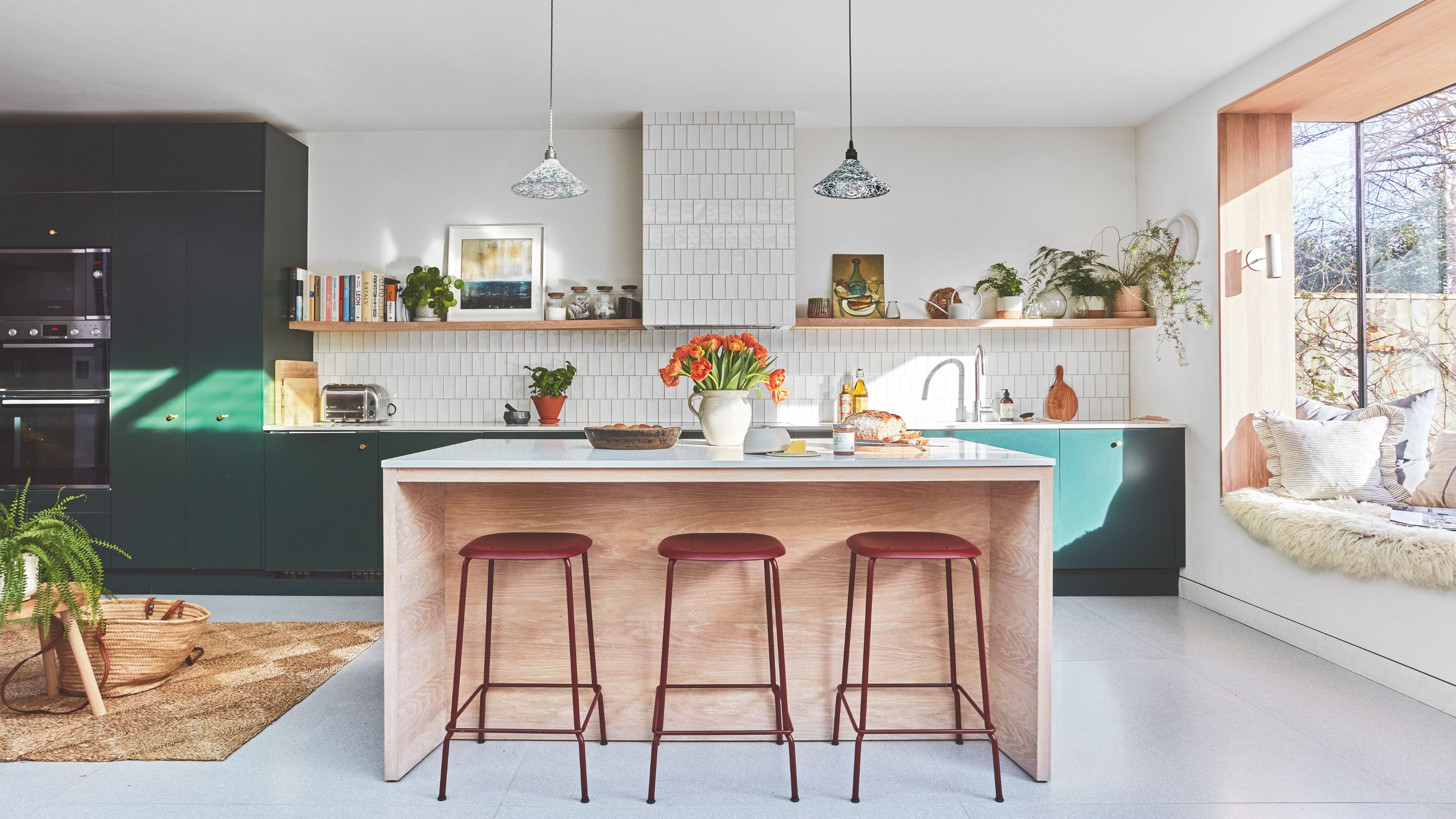Large kitchen area with dark teal cabinetry and a kitchen island with stools on one side of it