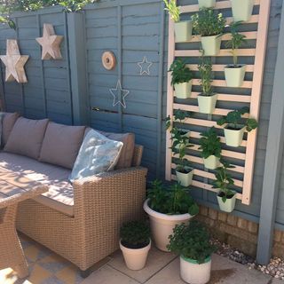 garden area with wooden wall and hanging plastic pots with plants