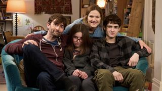 David Tennant as Simon, Miley Locke as Rosie, and Edan Hayhurst as Ben sit together on a sofa with Jessica Hynes as Emily behind them in There She Goes.