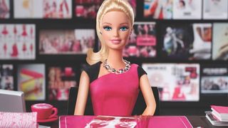 En Barbie-docka sitter vid ett skrivbord.