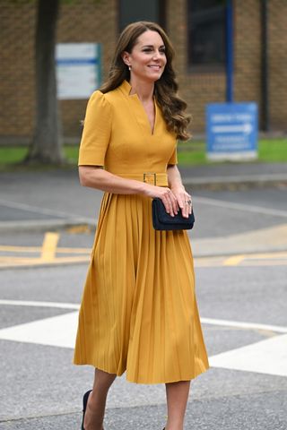 Catherine, Princess of Wales wears a yellow dress and a black clutch as she visits the Royal Surrey County Hospital's Maternity Unit at Royal Surrey County Hospital on October 05, 2022 in Guildford, England.