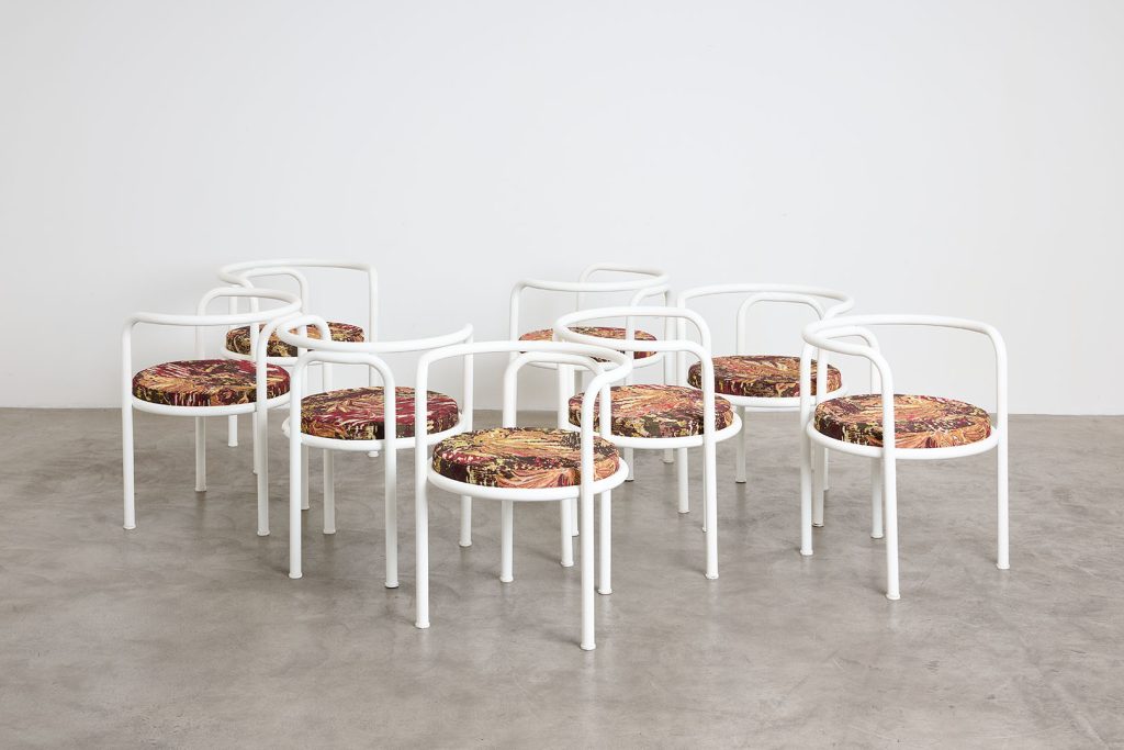 a cluster of white tubular steel chairs on concrete floor