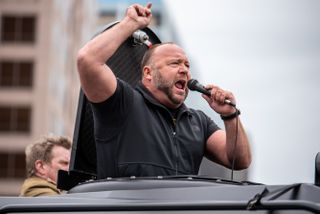 A close up of Alex Jones speaking into a microphone at a protest