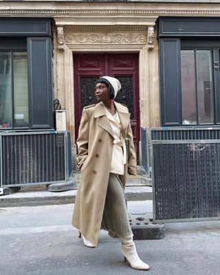 Franny in a beige long coat, cream boots and a skirt