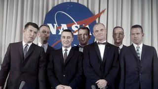 NASA's then-newly named Mercury 7 astronauts stand in front of a pre-finalized version of the agency's insignia in April 1959.