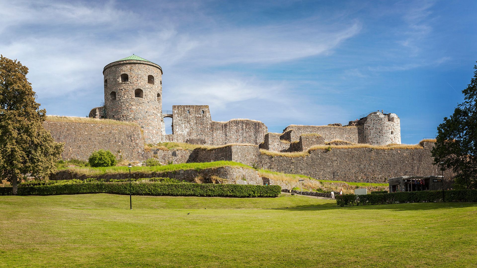 A view of a round stone turret next to a series of stone walls