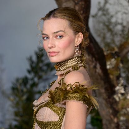 a white woman posing in front of a floral background at a movie premiere