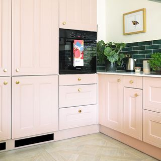 kitchen-diner with pink cabinets and built in oven