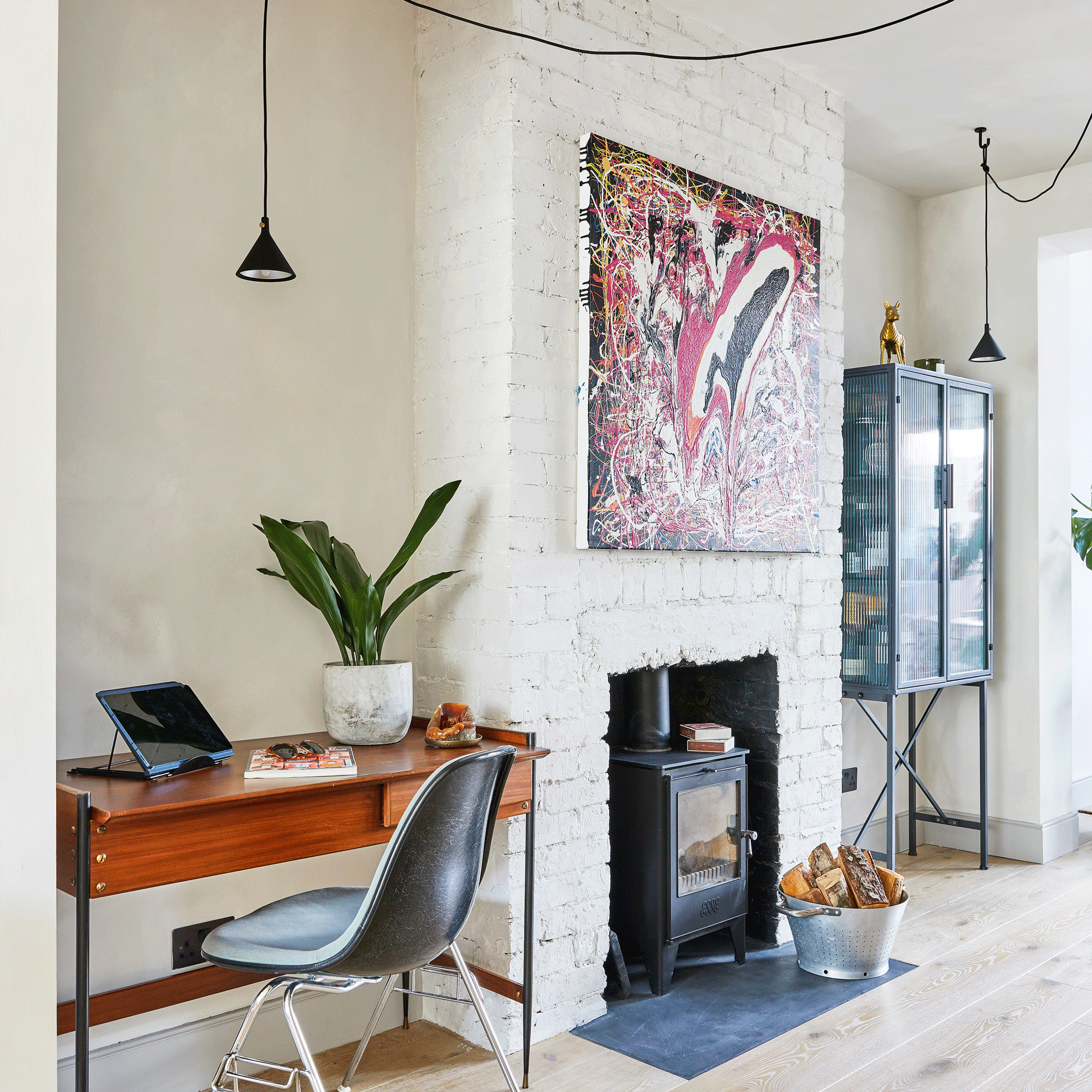 living room with a study area, desk and chair in one alcove, a fireplace with a woodburner and a glass fronted drinks cabinet in the other alcove
