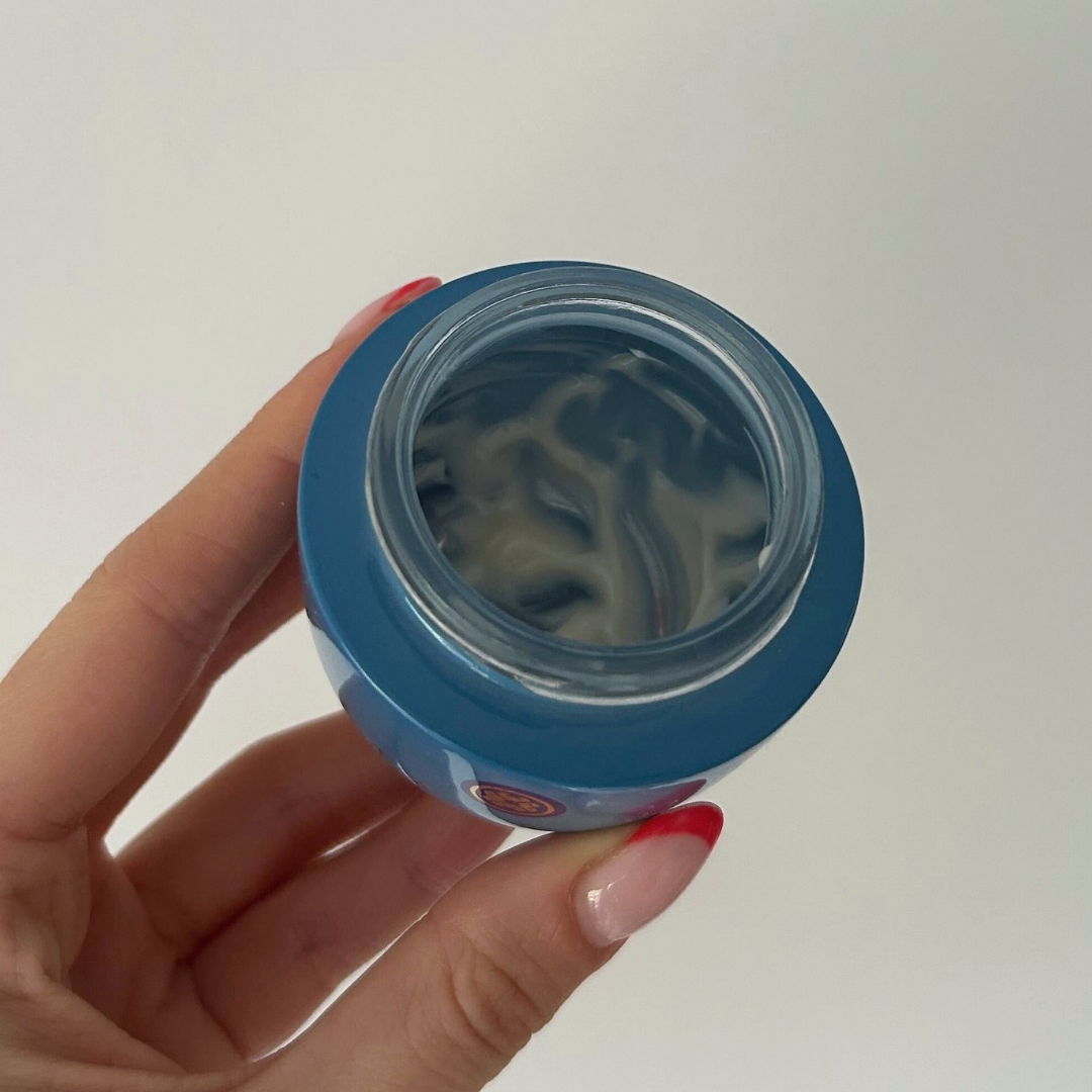 Hand holding empty blue tub of Tatcha Indigo Overnight Repair