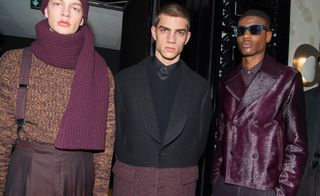 Three models in Maroon and black clothing posing for the camera, one with a large scarf and one with sunglasses