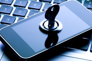 Locked touch screen phone lying on a blue illuminated keyboard.