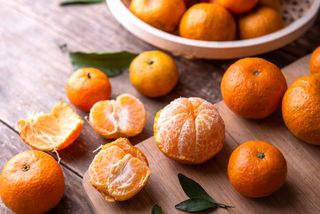 clementines scattered on a table some are unpeeled