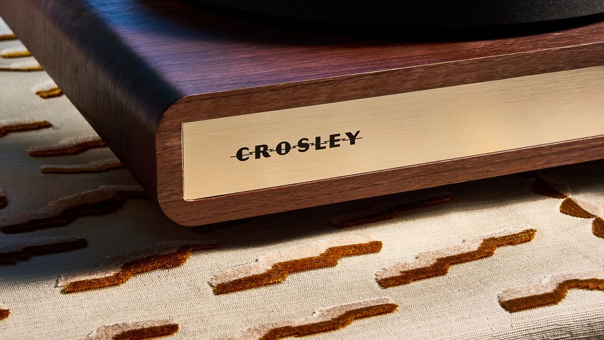 Crosley C65 turntable and bookshelf speakers photographed in front of a blue background on a brown table.