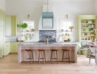 kitchen with lime green cabinets, limed wood island with barstools and breakfast area with banquette
