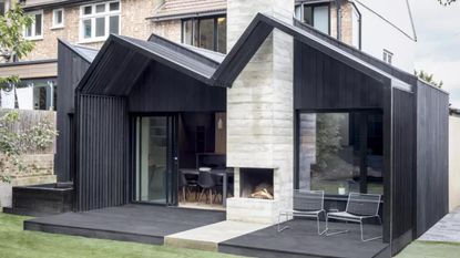 modern black exterior single storey extension by Gruff Architects with a black deck, with a brick house behind