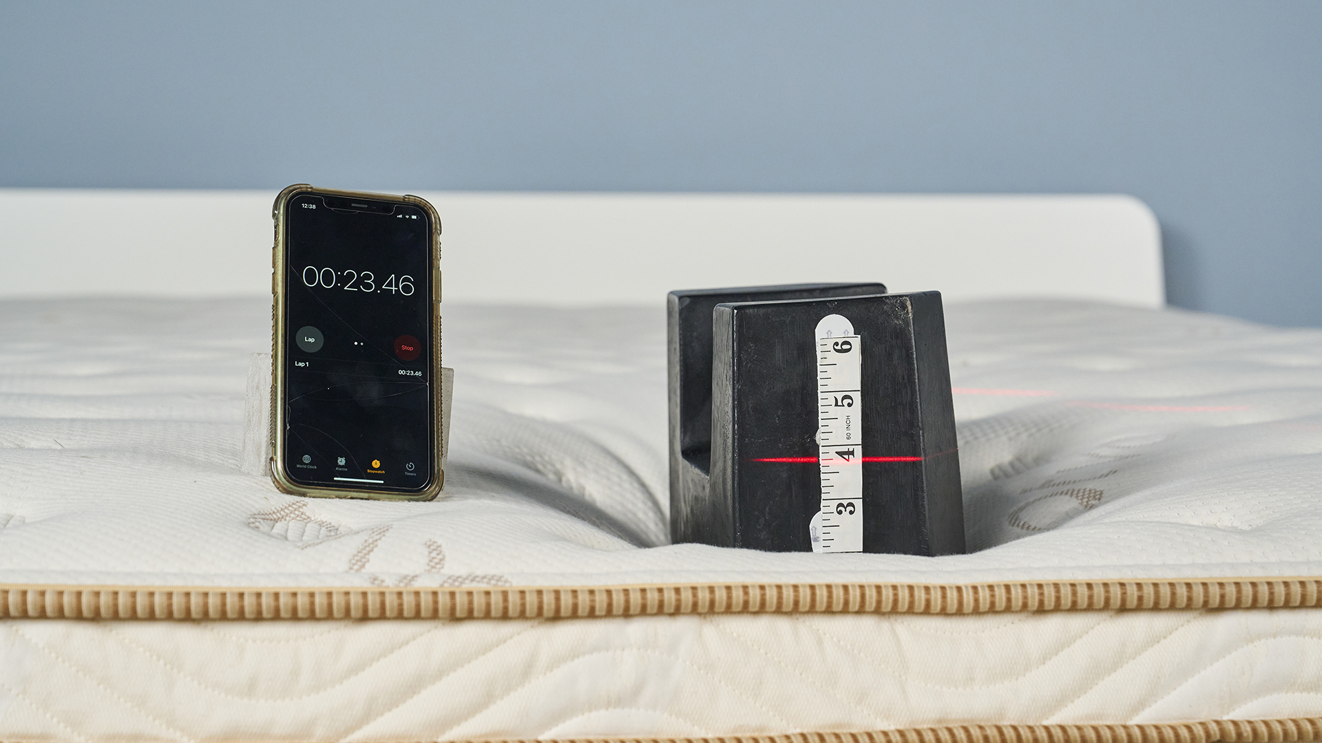 Edge support test using a cast iron 25kg weight on foot of the Saatva Classic mattress with digital laser giving us another visual way to track compression at the perimeter