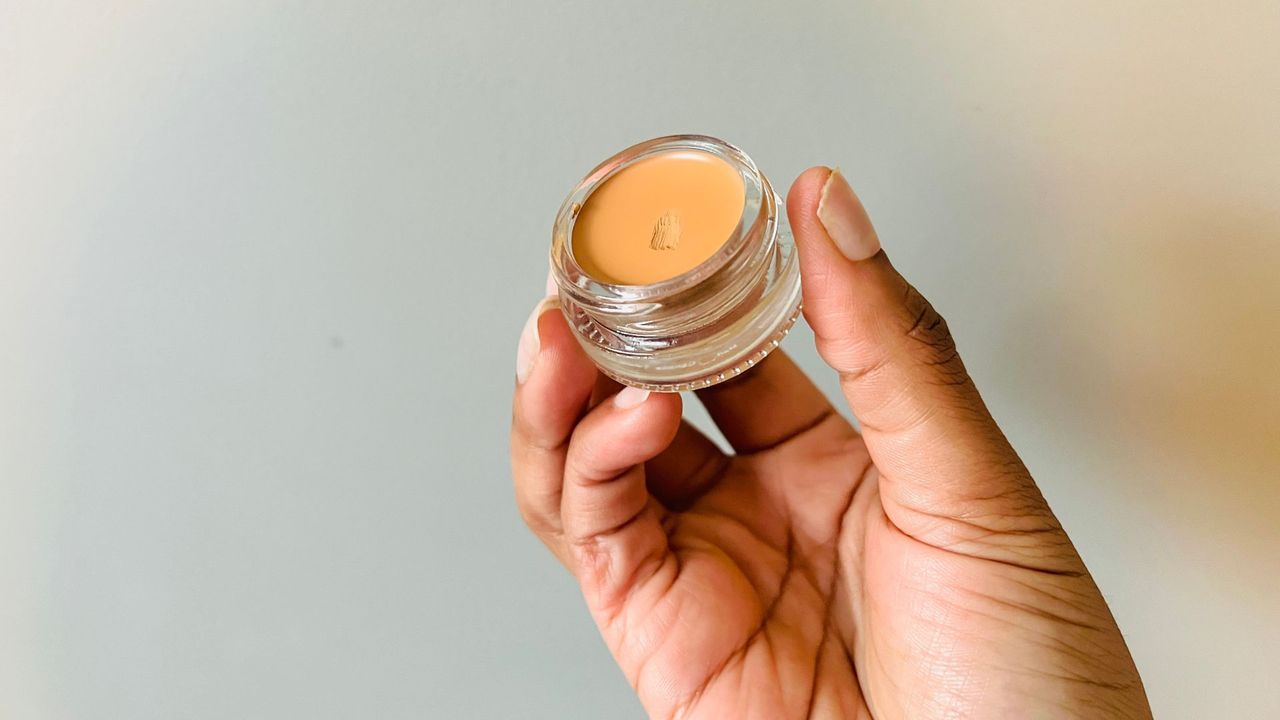 A person holding an opened Glossier Stretch Concealer for the best drugstore concealers.