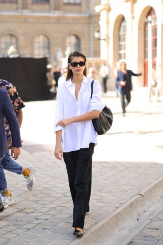 Kaia Gerber wearing a white button down with black trousers and black ballet flats