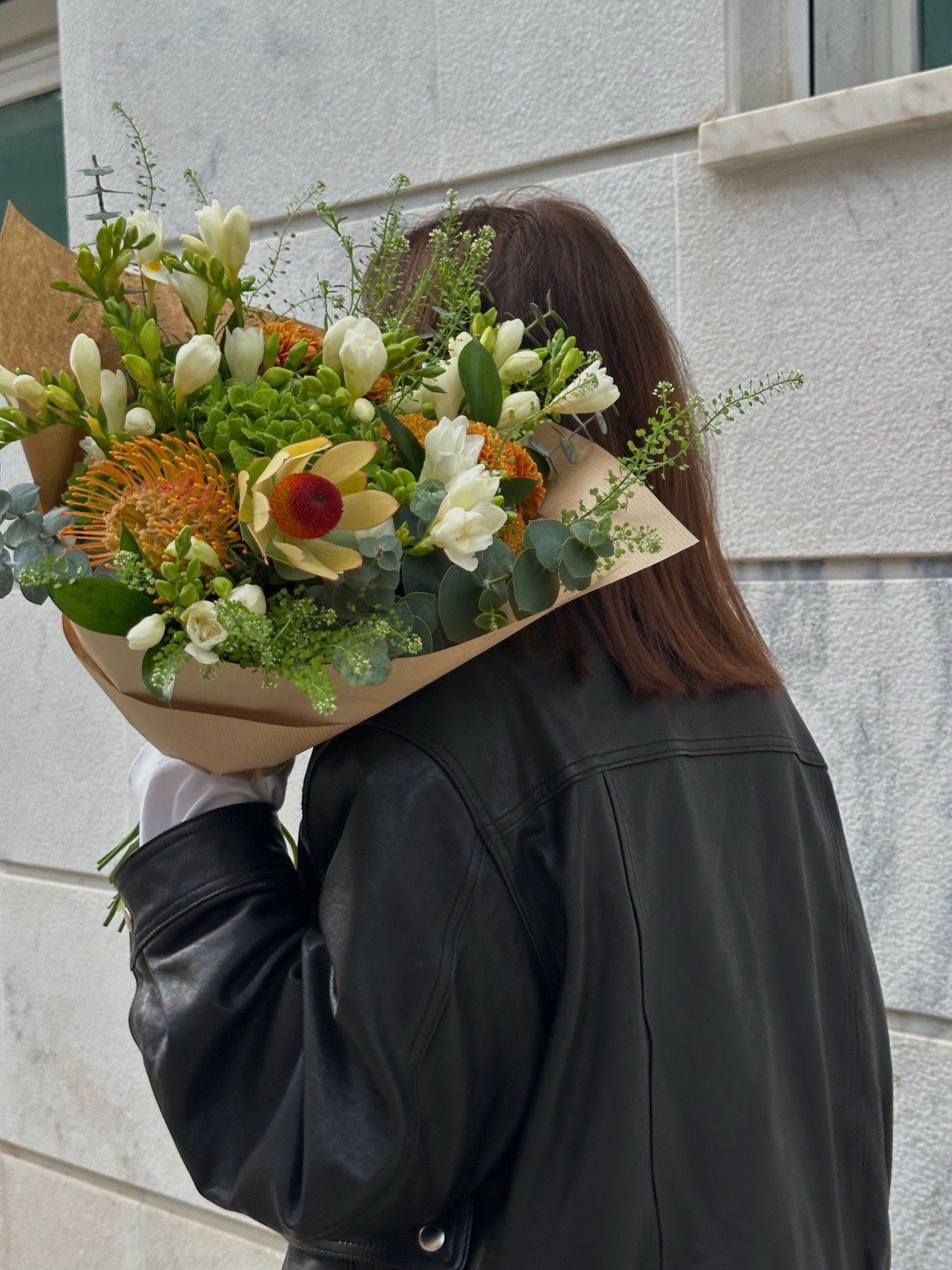 A woman carrying a colourful bouquet of flowers