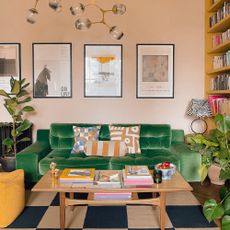 Soft pink living room with green velvet sofa and books stacked on a vintage coffee table