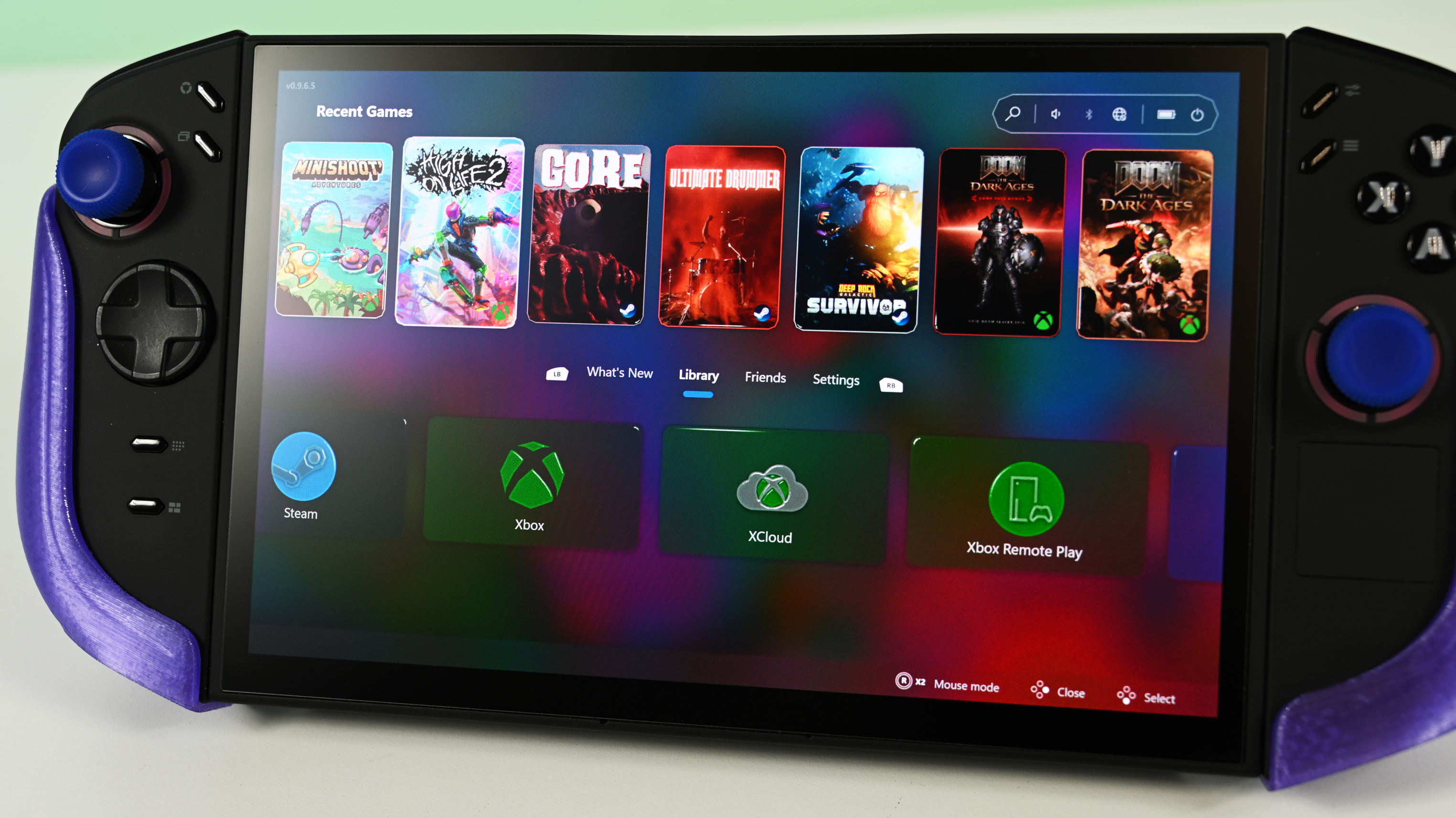 Lenovo Legion Go 2 running WinHanced, on a table displaying a games library screen. Colorful game covers and service icons like Steam and Xbox are visible.